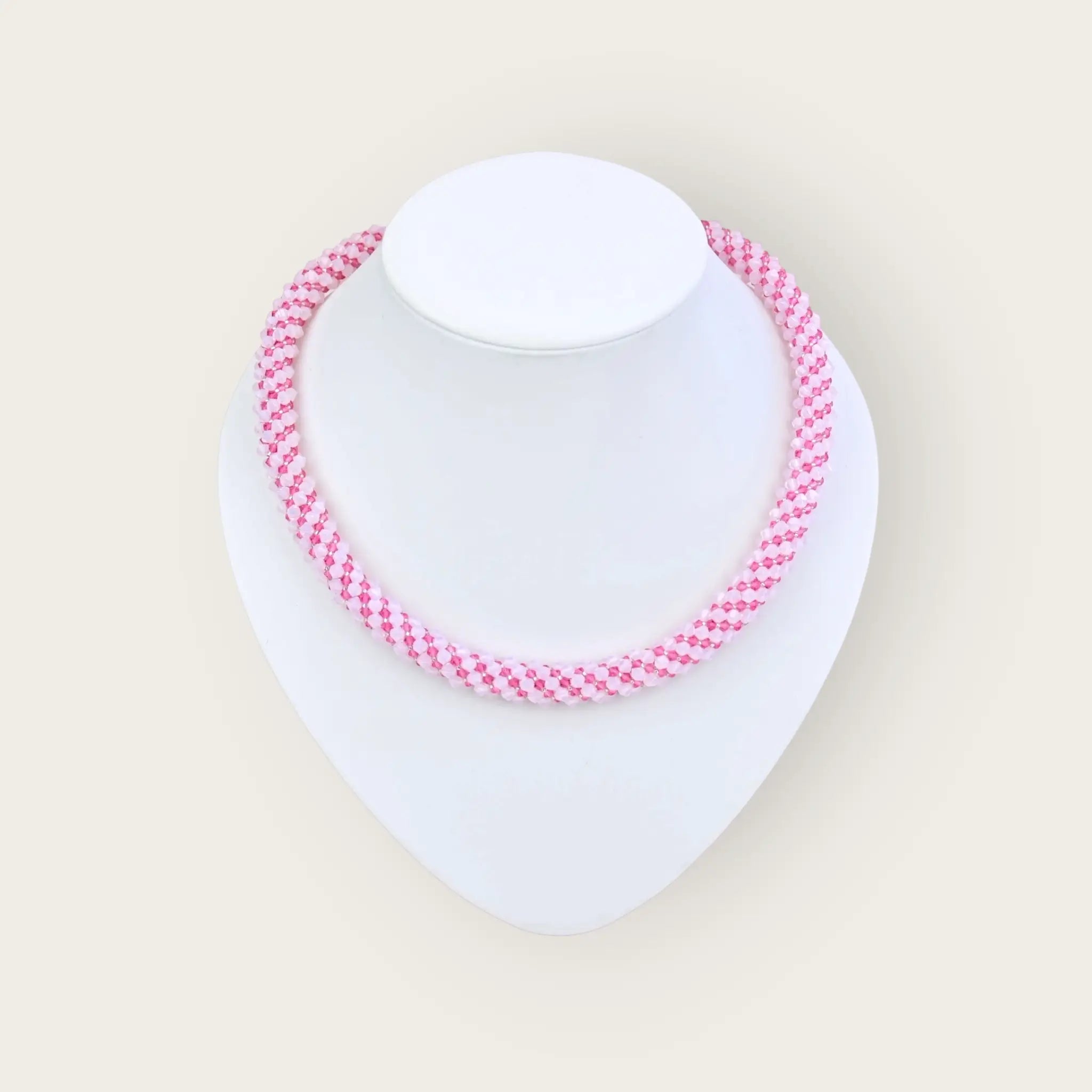 Elegante kette aus zarten rosa kristallperlen mit modischem houndstooth muster auf weißer mannequin bust